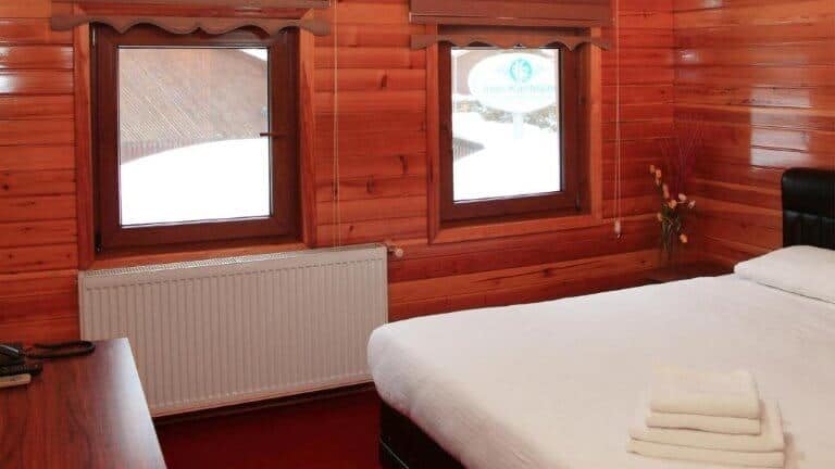 كوخ خشبي ريفي مع نوافذ وسرير